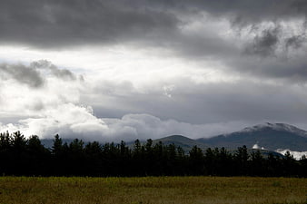 Dramatic cloudy sky over forest and mountain landscape
