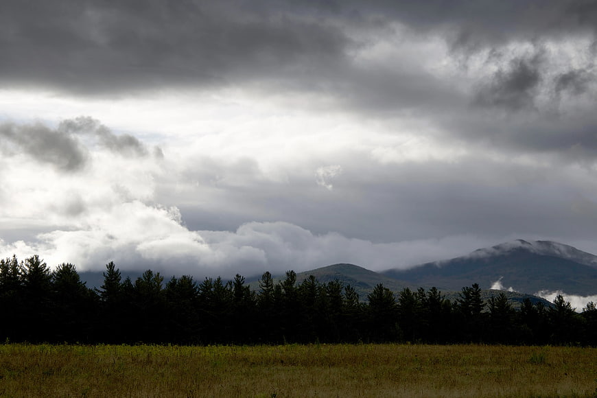 Dramatic cloudy sky over forest and mountain landscape