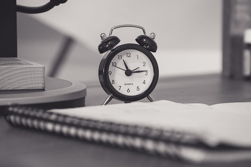 Black and white alarm clock on desk with notebook