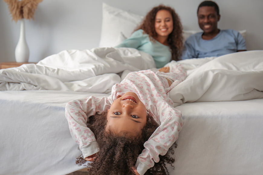 Happy family in bed with playful daughter upside down