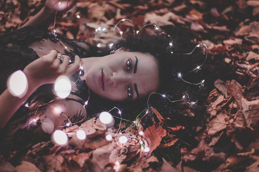 Woman Lying in Autumn Leaves with Fairy Lights