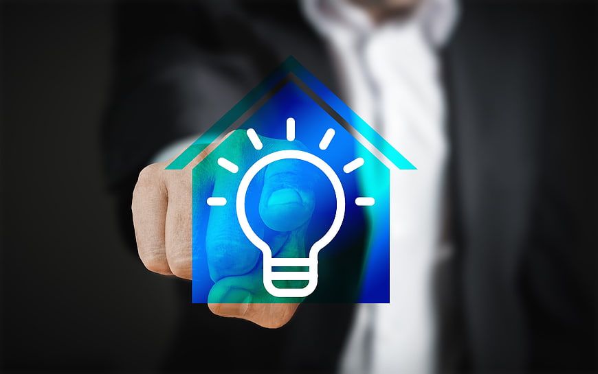 Businessman touching smart home light bulb icon on screen