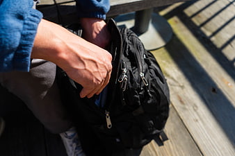 Close-up of hands packing a black backpack outdoors