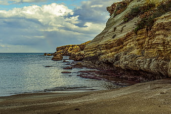 Dramatic coastal cliffs meeting the sea under cloudy skies