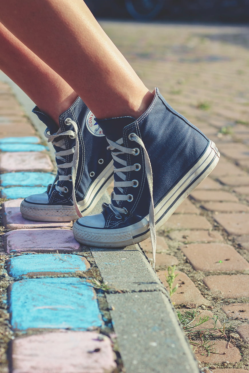 Blue denim high-top sneakers on colorful brick path