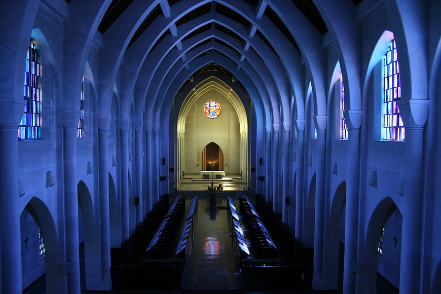 Blue lit cathedral interior with stained glass windows and altar