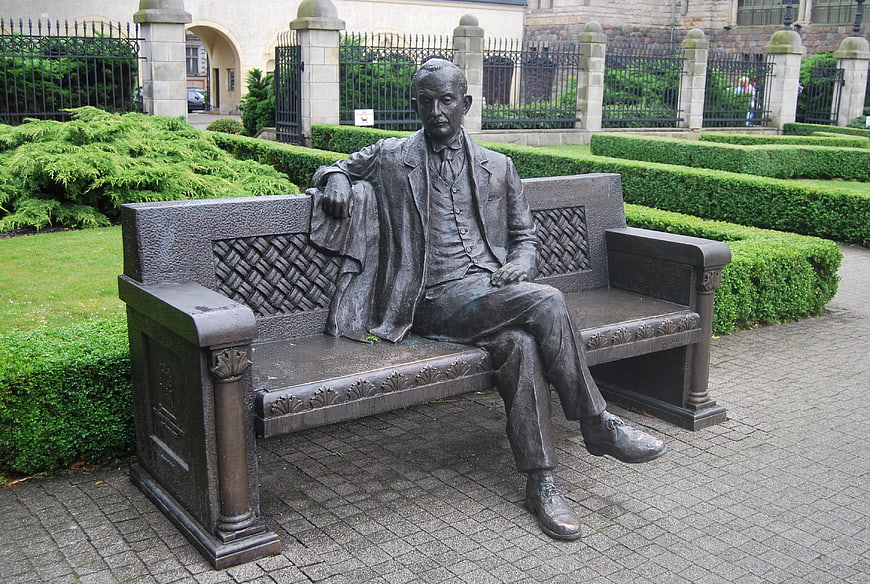 Bronze Statue of Man Sitting on Bench in Garden