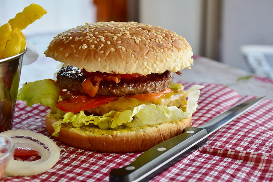Delicious Cheeseburger With Fries And Onion Rings On Checkered Tablecloth