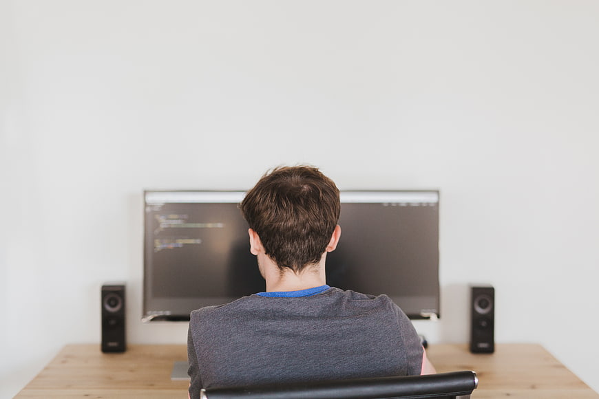 Back view of programmer coding at desk