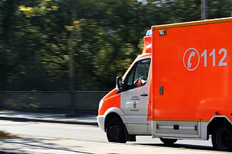 Orange emergency ambulance van driving on a city street