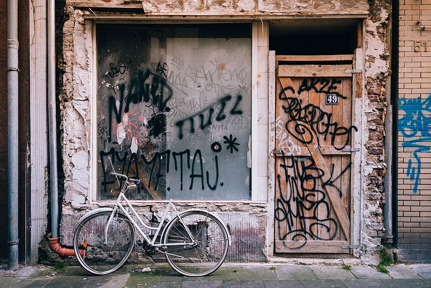 White Bicycle Parked in Front of Graffiti-Covered Urban Door