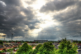 Dramatic sunbeams breaking through storm clouds over cityscape