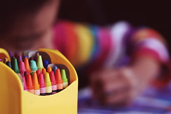 Colorful Crayons in Yellow Holder with Blurred Child