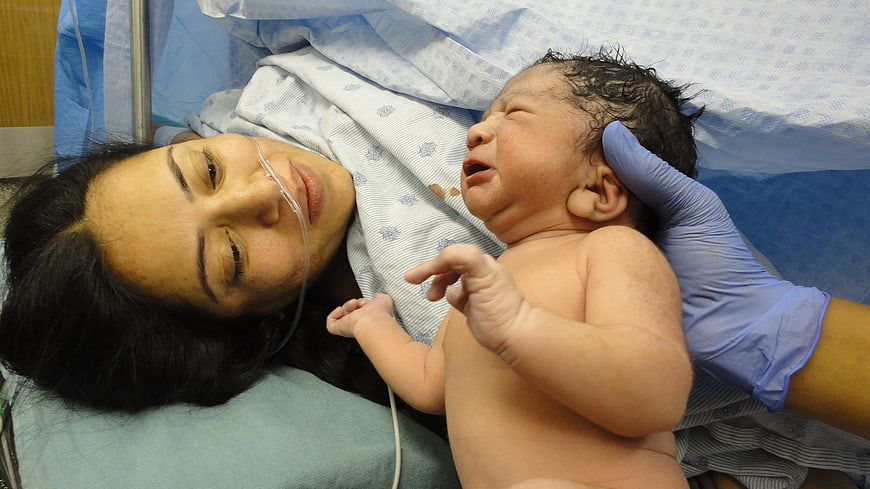Mother holding newborn baby immediately after birth in hospital