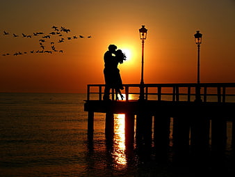 Silhouette of Lovers Kissing on Pier at Sunset