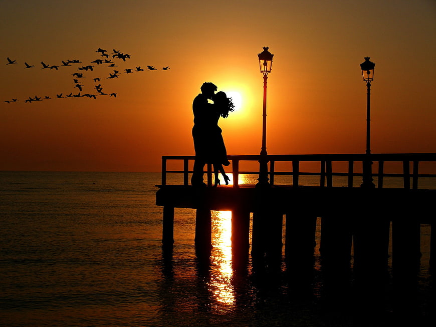 Silhouette of Lovers Kissing on Pier at Sunset