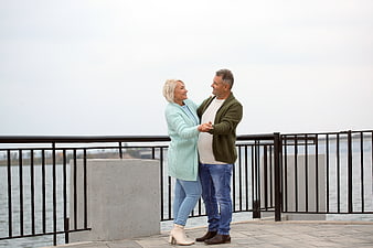 Happy senior couple dancing outdoors by the water