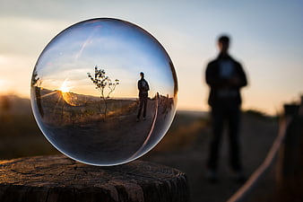 Crystal Ball Photography of Man on Hill at Sunset