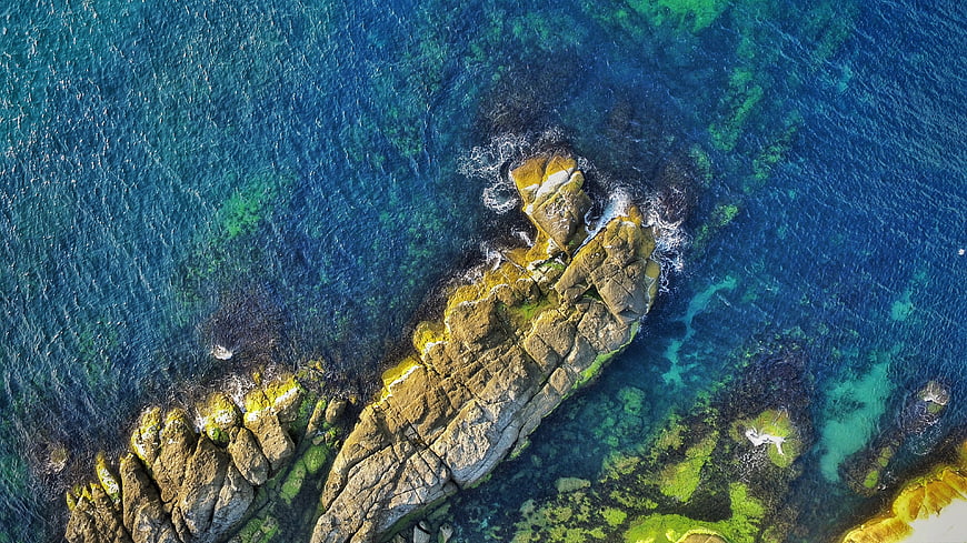 Aerial View of Rocky Coastline in Turquoise Ocean Water