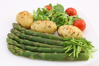 Healthy vegetable plate with asparagus, potatoes, salad, and cherry tomatoes