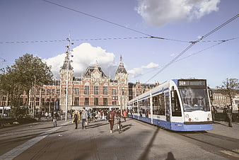 Blue and white tram passing Amsterdam Central Station