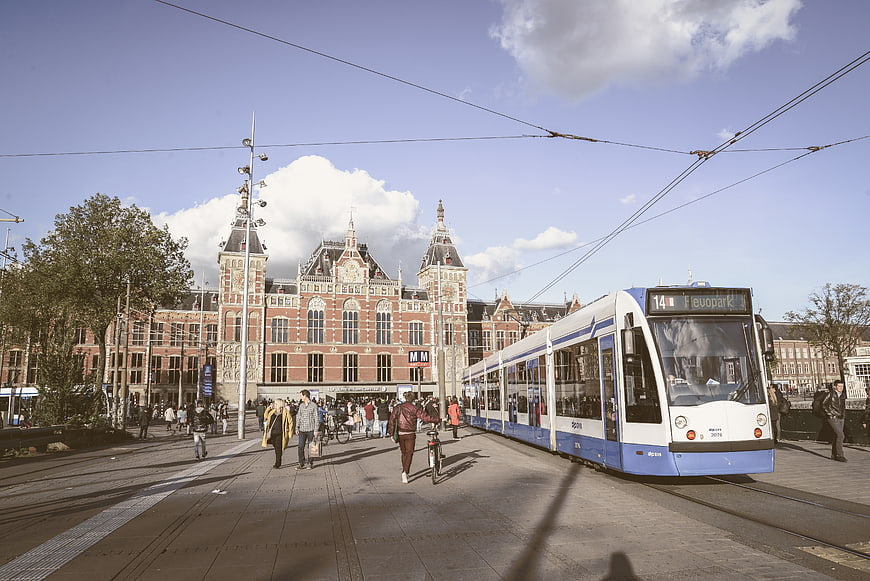 Blue and white tram passing Amsterdam Central Station