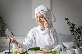 Woman with cucumber slice on face doing skincare routine