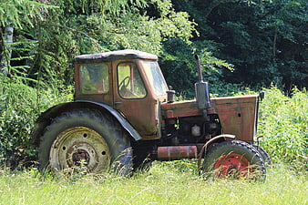 Rusty vintage tractor abandoned in overgrown green field