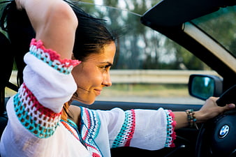 Happy woman driving convertible car with colorful crochet top