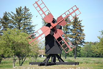 Red and black wooden windmill in a green field