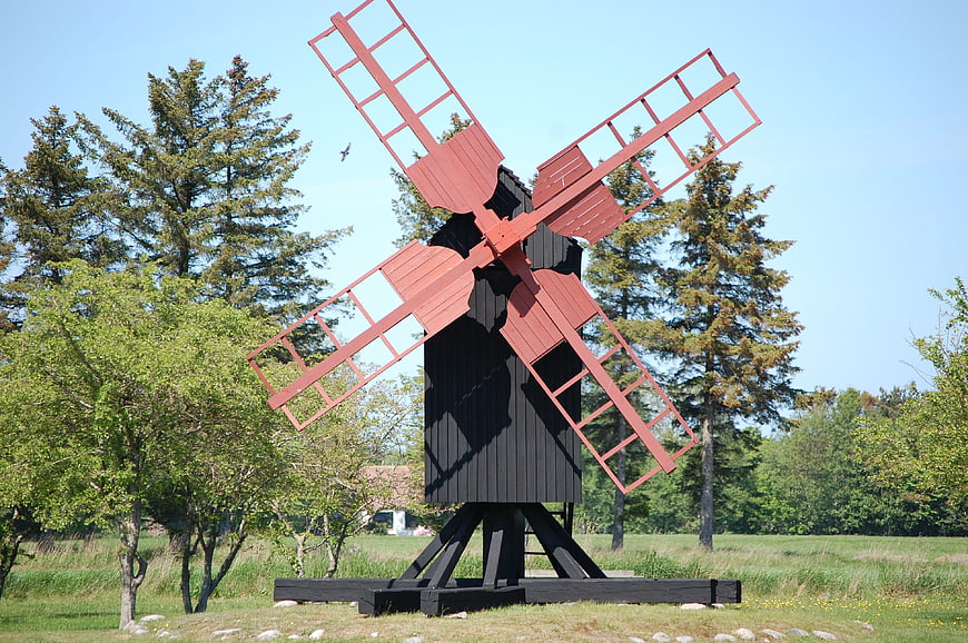 Red and black wooden windmill in a green field