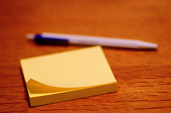Yellow sticky note pad and pen on wooden desk