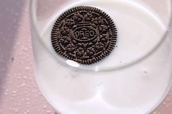 Top view of Oreo cookie floating in glass of milk