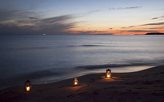 Romantic Lanterns on Sandy Beach at Sunset