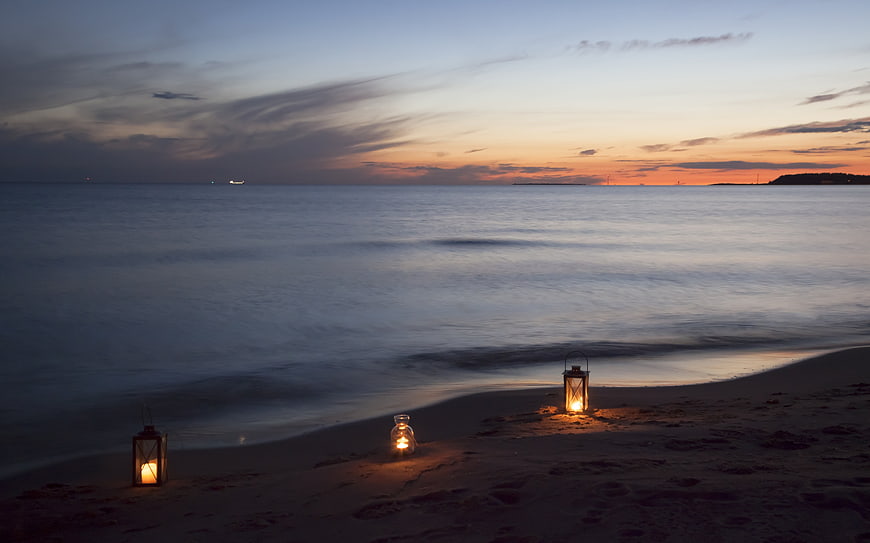 Romantic Lanterns on Sandy Beach at Sunset