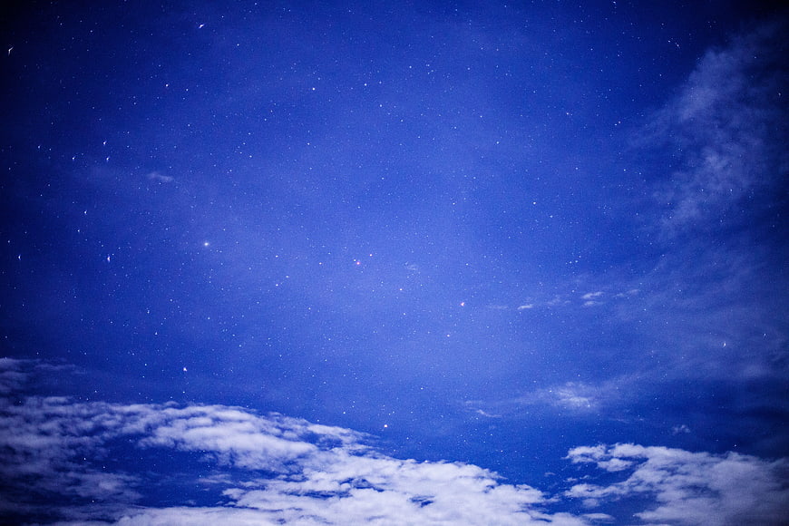 Starry Night Sky with Wispy Clouds and Deep Blue Atmosphere
