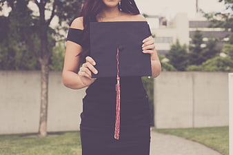 Woman holding black graduation cap with pink tassel