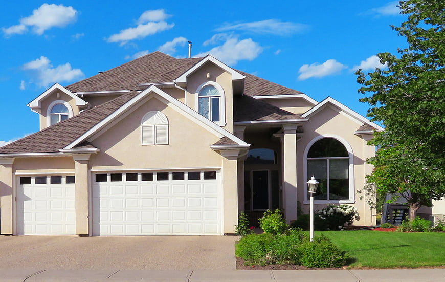 Beige suburban house with double garage and blue sky