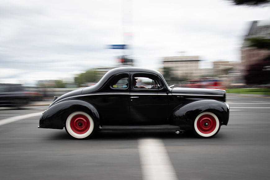 Black vintage hot rod driving fast on city street