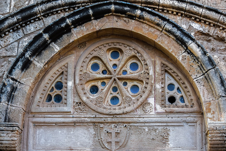 Medieval stone church facade with carved rose window and cross