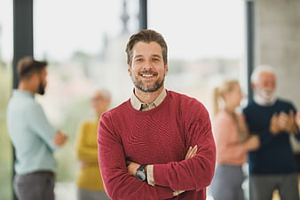 Confident Smiling Businessman in Red Sweater with Team