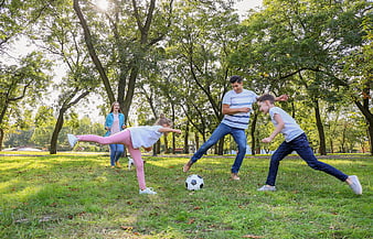 Happy family playing soccer together in a sunny park