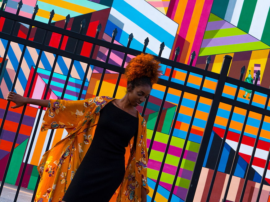 Woman in floral kimono posing against colorful geometric mural