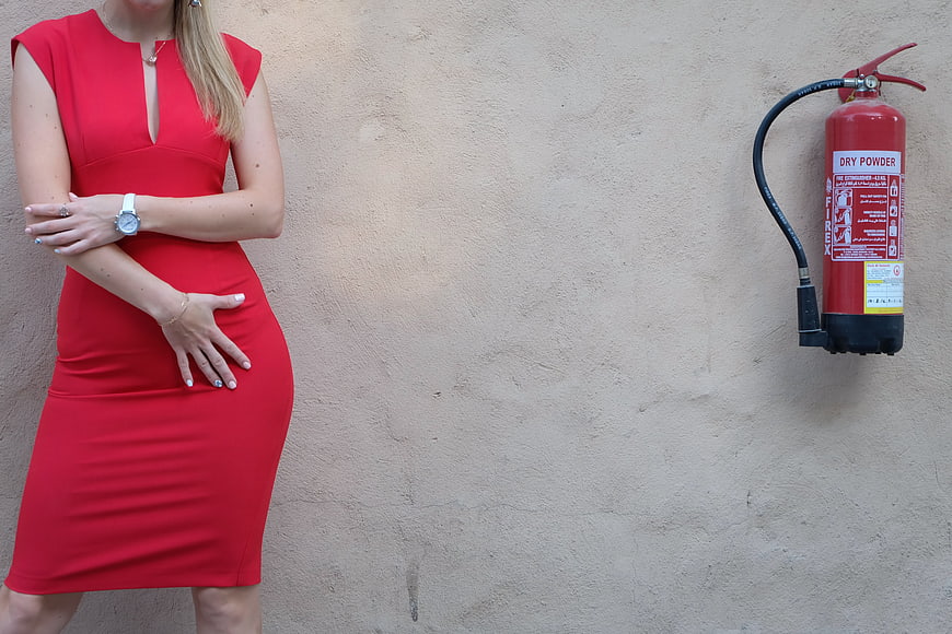 Woman in Red Dress Standing Next to Fire Extinguisher