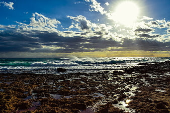 Dramatic Rocky Coastline with Sunbeams and Ocean Waves