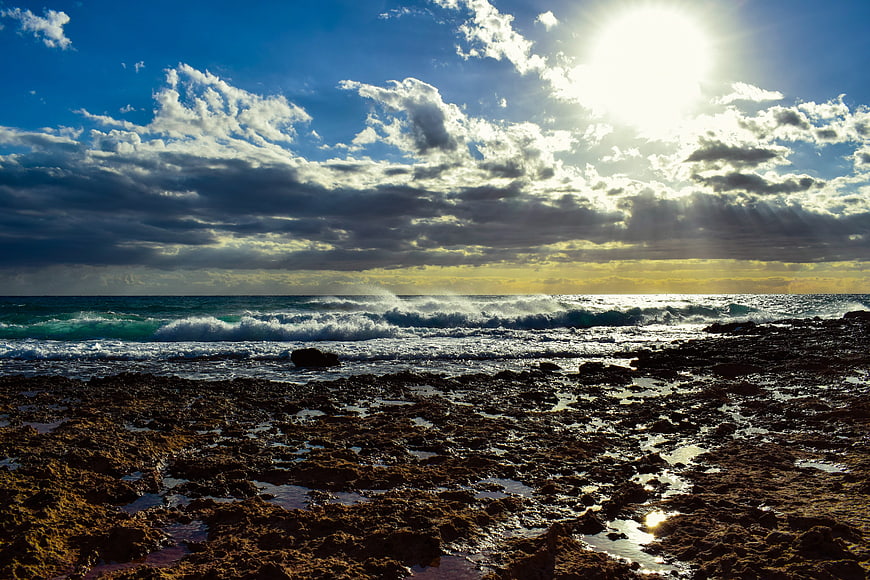 Dramatic Rocky Coastline with Sunbeams and Ocean Waves