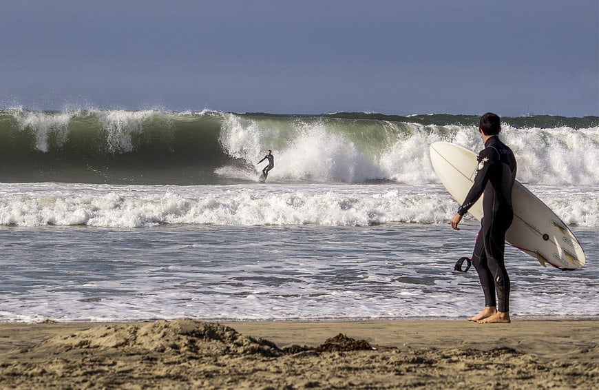 Surfer Watching Wave on Sandy Beach