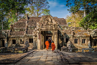 Monks in Orange Robes Walking Through Ancient Khmer Temple Ruins in Cambodia