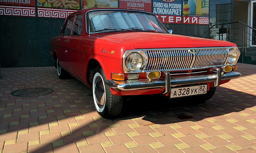 Classic Red Volga Sedan Parked On Paved Street