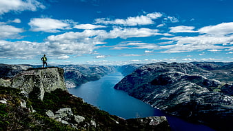Hiker standing on cliff overlooking fjord landscape